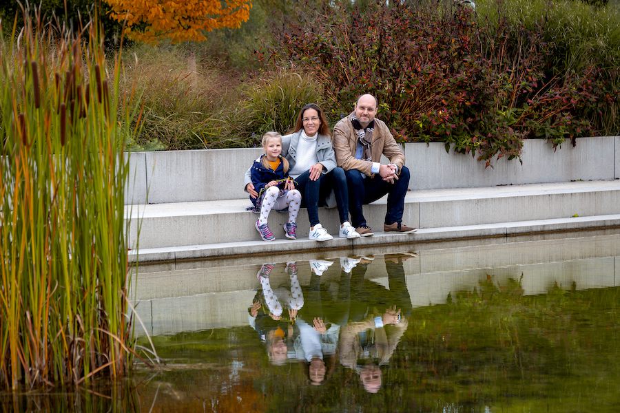 Familie mit Kind auf einer Steintreppe vor einem See