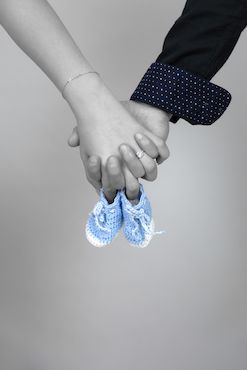 Bild von zwei Händen, die Babyschuhe halten