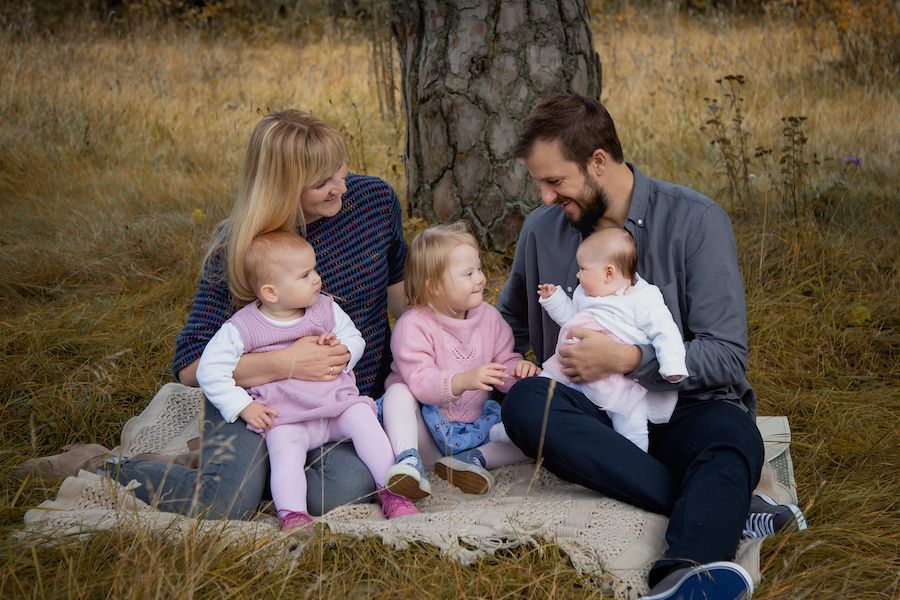 Familie sitzt auf einer Decke vor einem Baum