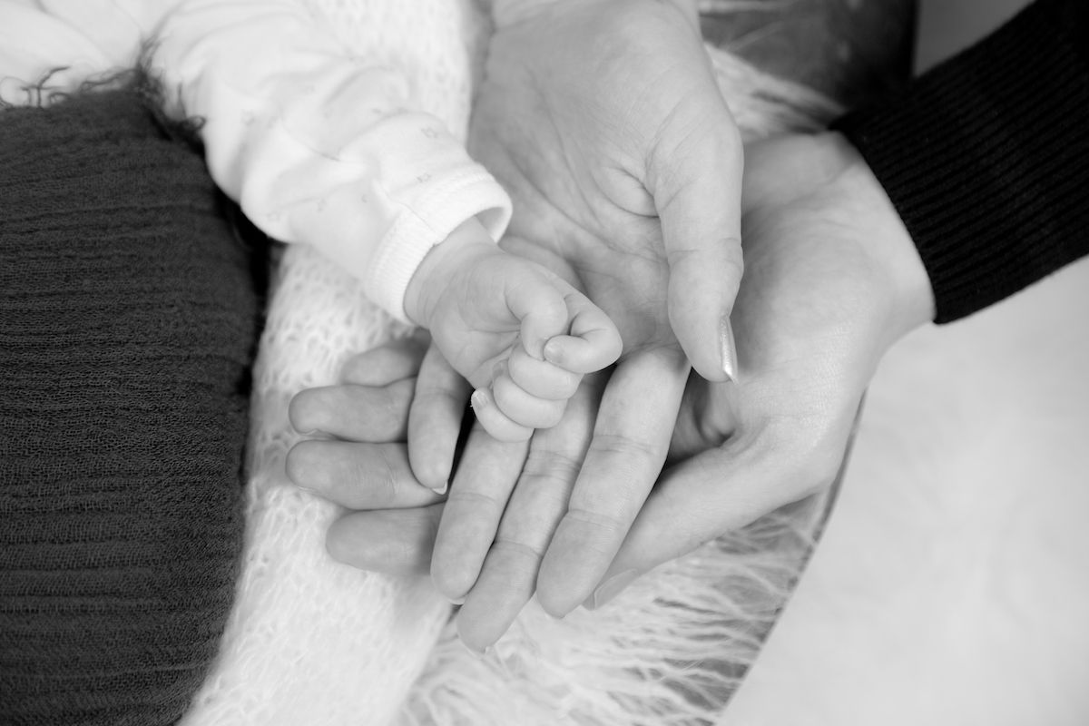 Hände von Eltern mit der Hand ihres Babys