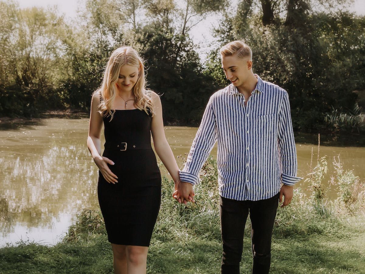 Bild eines jungen Paars Hand in Hand vor einem See