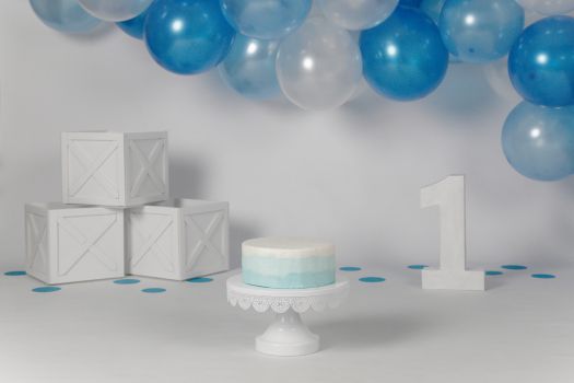 Symbolbild einer Torte mit Luftballons, Kisten und einer Zahl 1 aus Holz