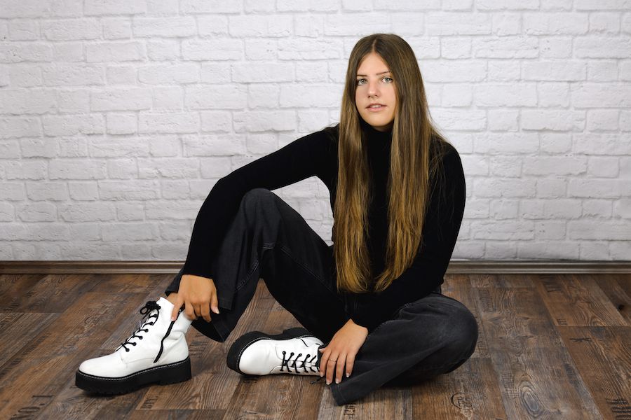 Jugendliche auf dem Boden vor einer Steinwand sitzend