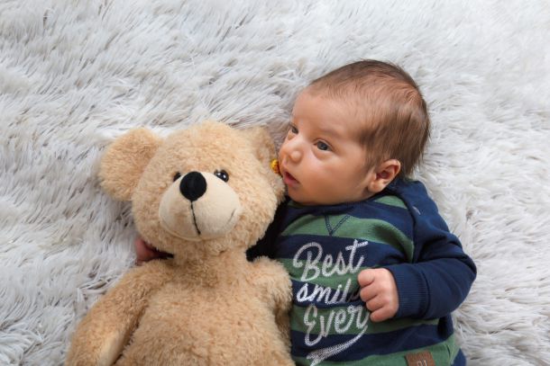 Baby auf Decke liegend mit Kuscheltier