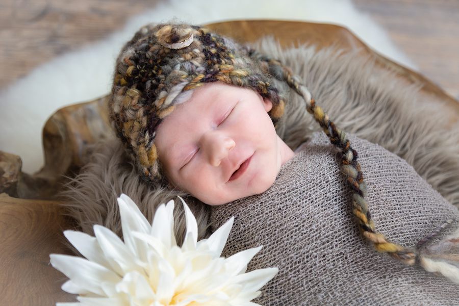 Schlafendes Baby mit Mütze und Blüte